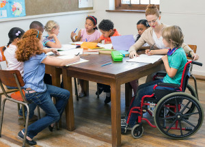 Pretty teacher helping pupils in classroom